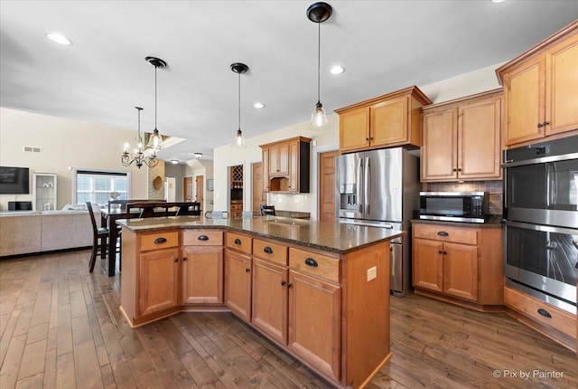 kitchen featuring stainless steel appliances, a kitchen island, open floor plan, backsplash, and dark wood-style floors