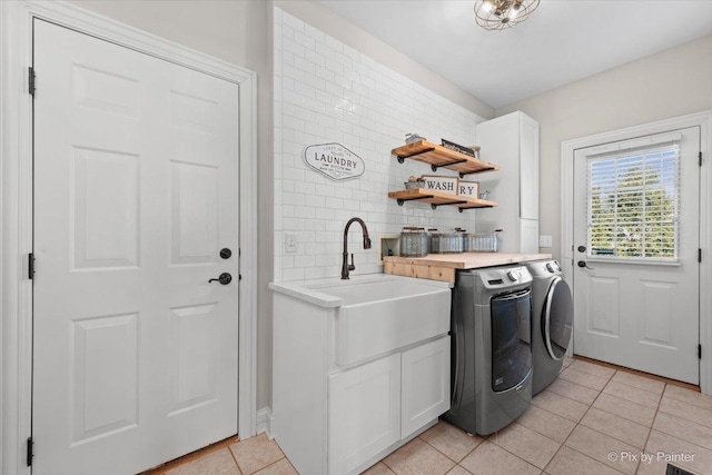 laundry room with washing machine and dryer, cabinet space, a sink, and light tile patterned floors