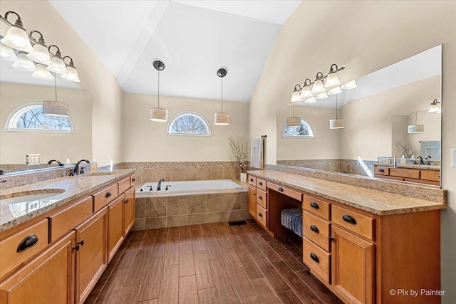 full bath featuring a bath, plenty of natural light, a sink, and wood finished floors