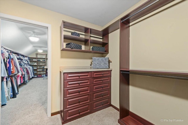 walk in closet featuring vaulted ceiling and carpet