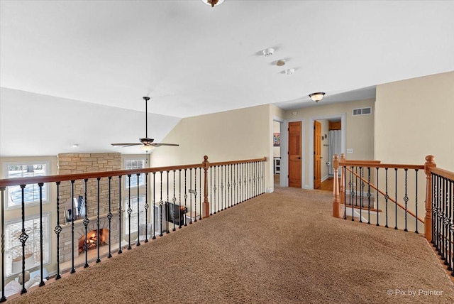 hall featuring lofted ceiling, carpet floors, an upstairs landing, and visible vents