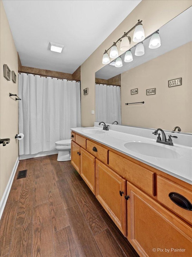 full bath with double vanity, wood finished floors, a sink, and visible vents