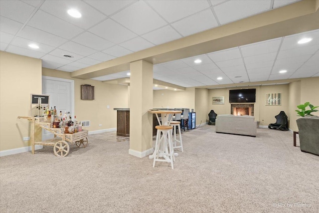 game room with a bar, a paneled ceiling, baseboards, and carpet flooring