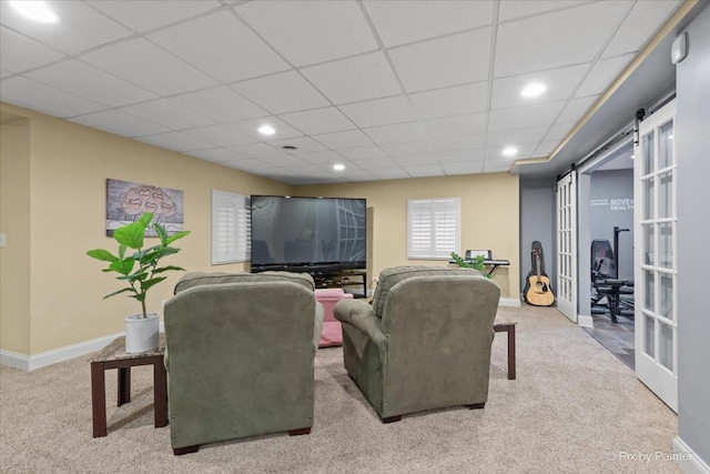 living room featuring a paneled ceiling, carpet, and baseboards