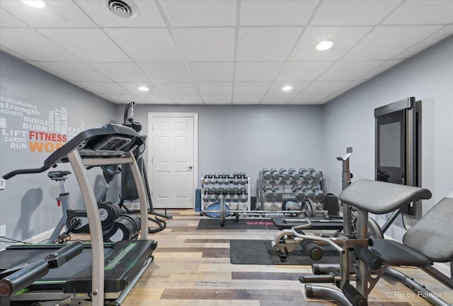 exercise area with a drop ceiling, recessed lighting, wood finished floors, visible vents, and baseboards