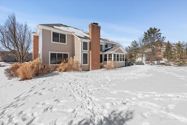 snow covered house featuring a chimney