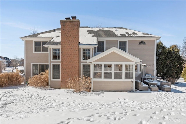 snow covered property with a chimney