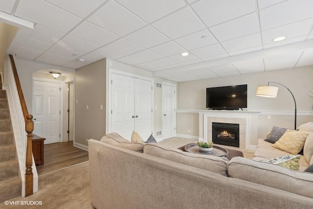 living room featuring a tile fireplace and a drop ceiling