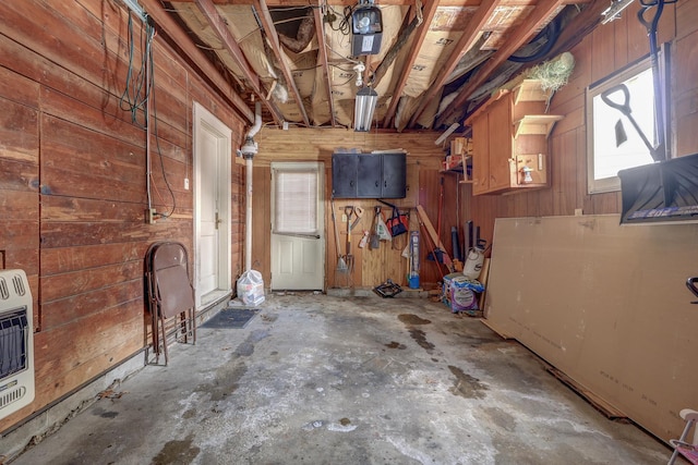 interior space featuring concrete flooring, heating unit, and wood walls