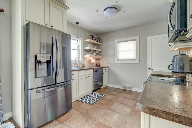 kitchen featuring sink, decorative light fixtures, light tile patterned floors, appliances with stainless steel finishes, and cream cabinets