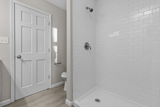 bathroom featuring hardwood / wood-style floors, toilet, and tiled shower