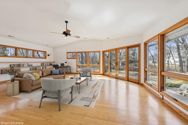 living area with ceiling fan, lofted ceiling, and light wood-style flooring