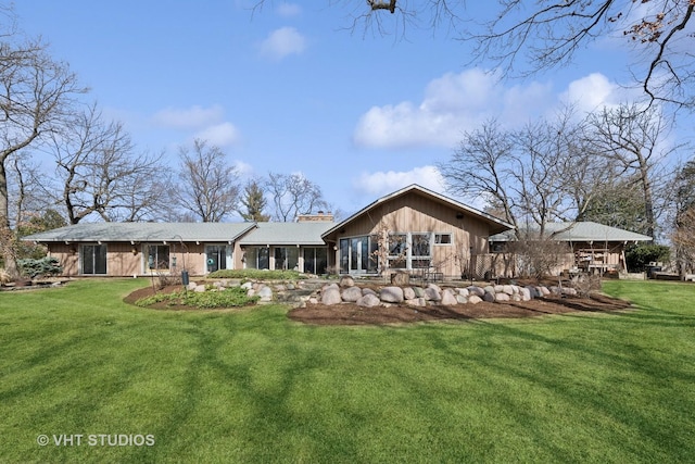 rear view of property with a chimney, a yard, and a sunroom