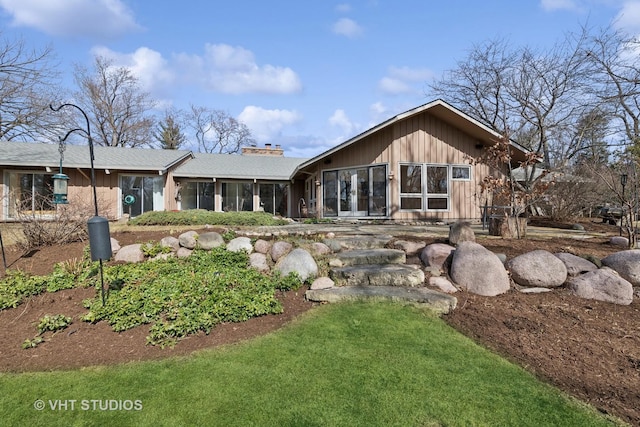 back of property featuring french doors, a sunroom, and a chimney