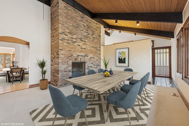 carpeted dining area featuring an outdoor brick fireplace, beam ceiling, a healthy amount of sunlight, and visible vents