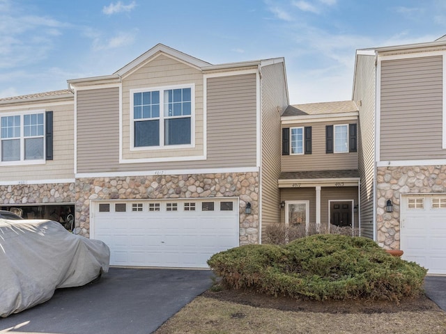 view of front of property with an attached garage, stone siding, and driveway