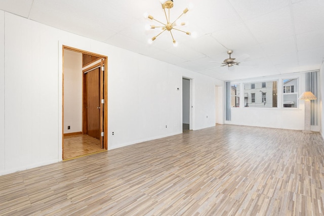 empty room with ceiling fan with notable chandelier and light hardwood / wood-style flooring