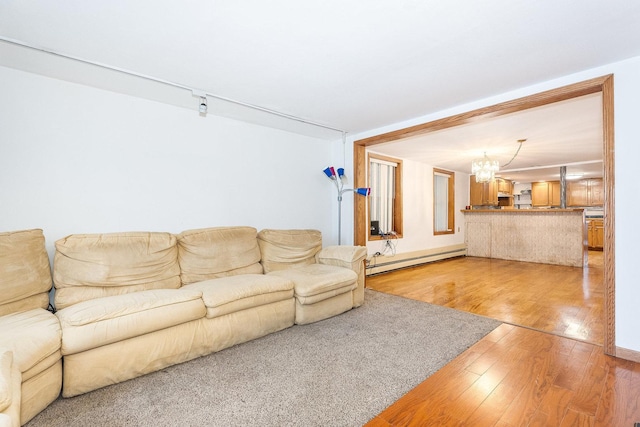 living room featuring an inviting chandelier, wood-type flooring, and baseboard heating