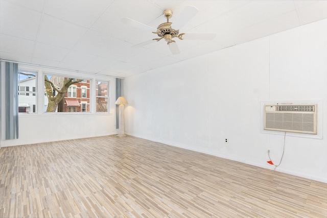 empty room featuring light hardwood / wood-style flooring, a wall unit AC, and ceiling fan