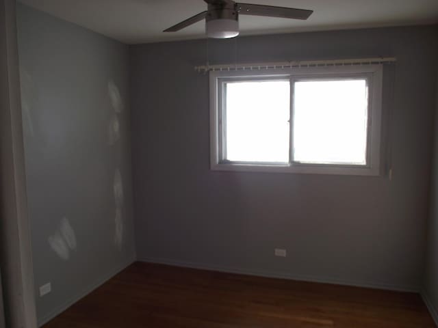 unfurnished room with dark wood-style floors, ceiling fan, and baseboards