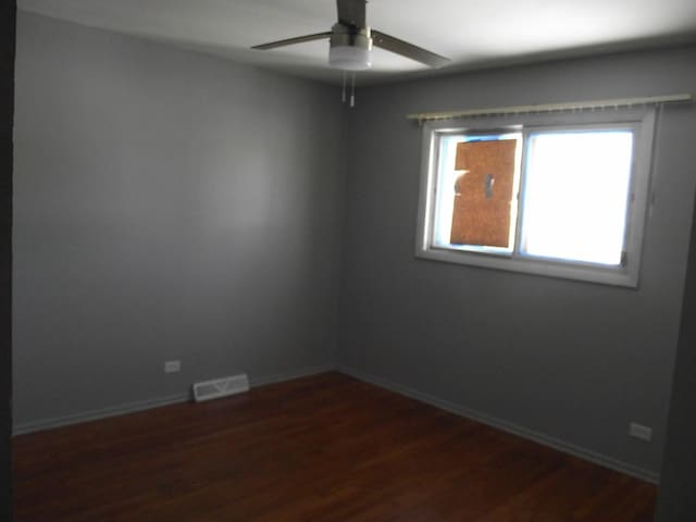 unfurnished room featuring visible vents, baseboards, ceiling fan, and dark wood-style flooring