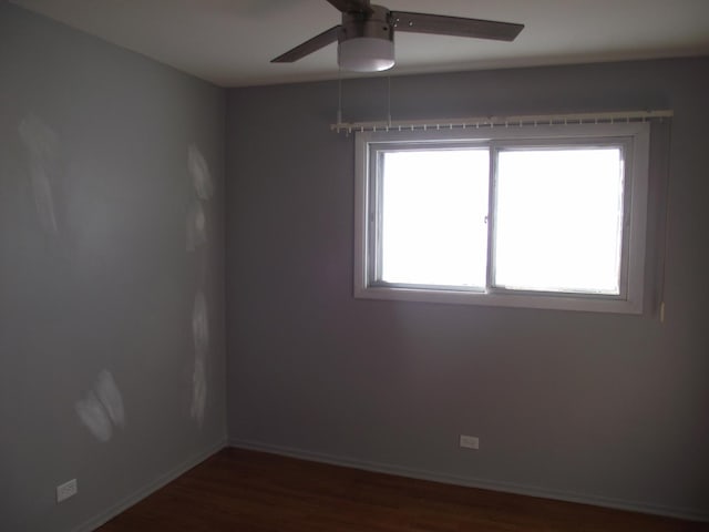 spare room with dark wood-type flooring, baseboards, and a ceiling fan