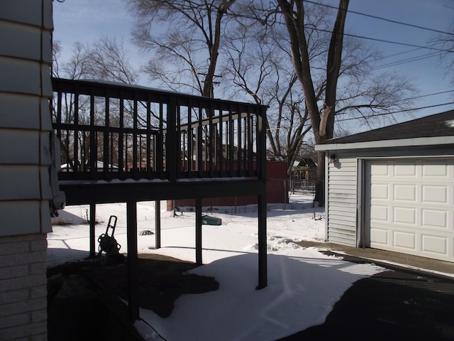 snow covered deck featuring a garage and an outbuilding