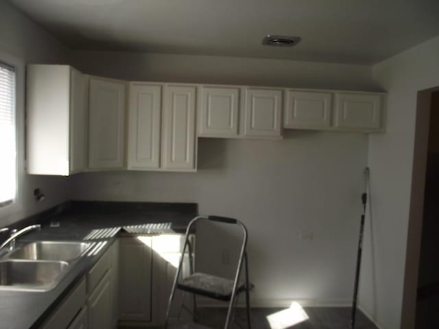 kitchen with dark countertops, white cabinets, and a sink