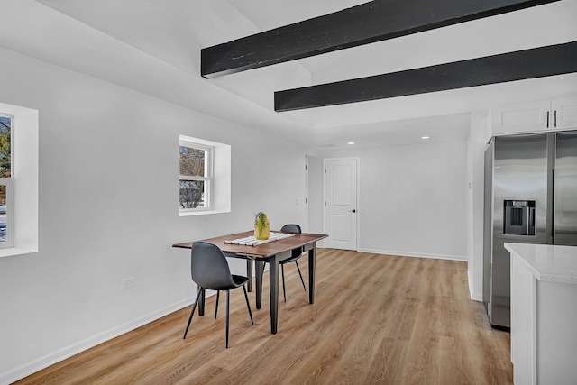 dining room with light hardwood / wood-style floors and beamed ceiling