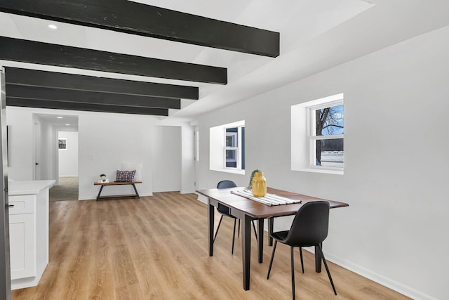 dining area featuring beam ceiling and light hardwood / wood-style flooring