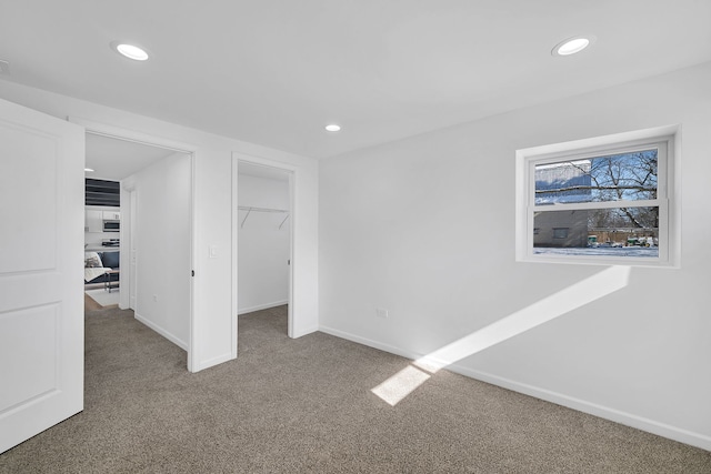 unfurnished bedroom featuring a spacious closet, a closet, and carpet flooring