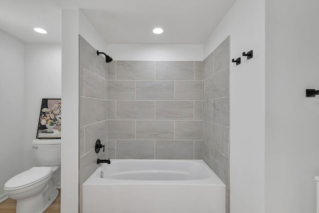 bathroom with tiled shower / bath combo and toilet