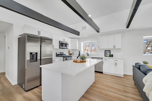 kitchen featuring stainless steel appliances, a center island, white cabinets, and beamed ceiling