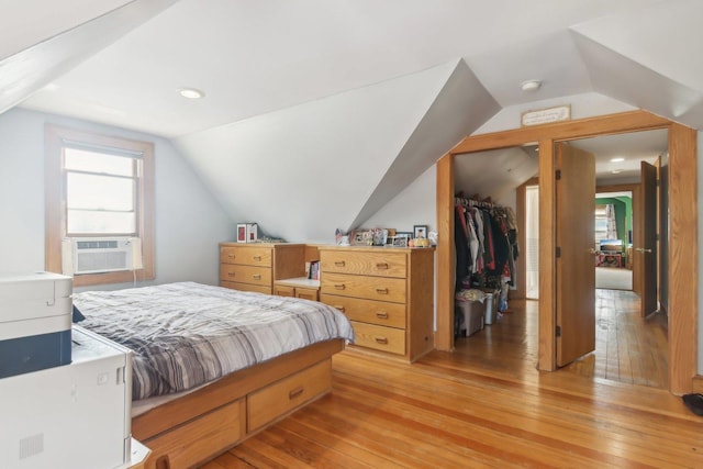 bedroom featuring lofted ceiling, cooling unit, light wood-style flooring, and a spacious closet