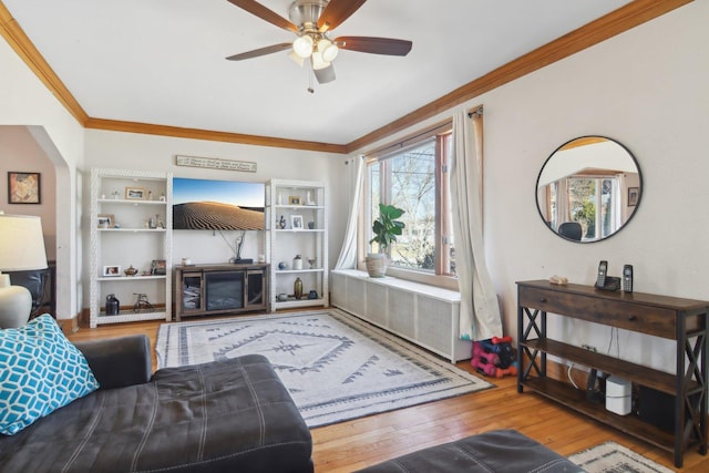 living area with crown molding, wood-type flooring, a ceiling fan, and radiator