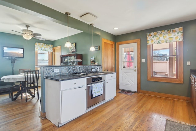 kitchen with stainless steel appliances, a wealth of natural light, light wood-style floors, and dark countertops