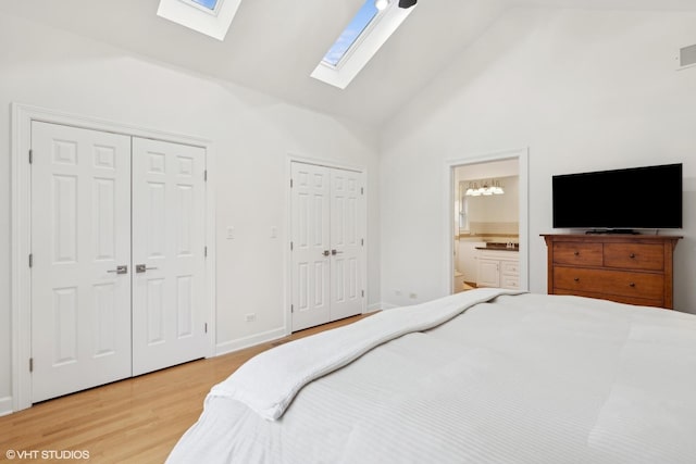 bedroom with visible vents, connected bathroom, wood finished floors, high vaulted ceiling, and two closets