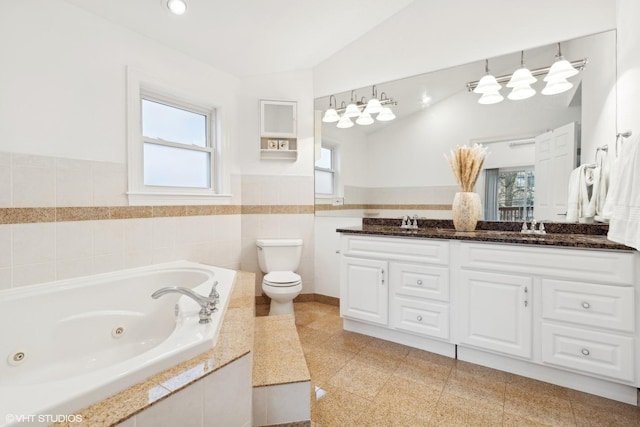 bathroom featuring double vanity, toilet, a wainscoted wall, lofted ceiling, and granite finish floor