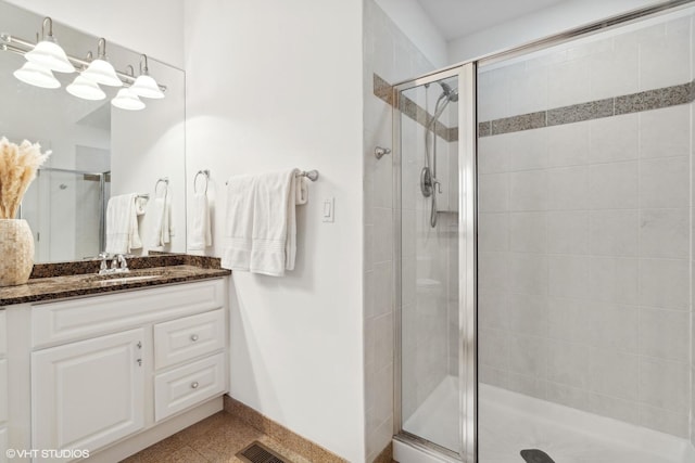 bathroom featuring baseboards, visible vents, a shower stall, and vanity