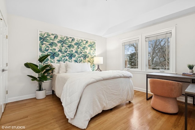 bedroom with vaulted ceiling, baseboards, and wood finished floors