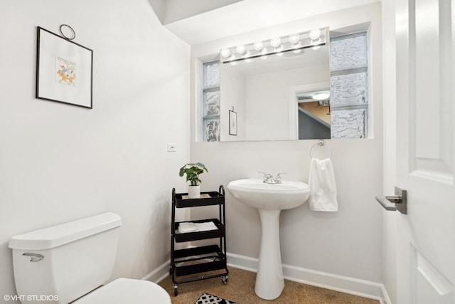 bathroom featuring toilet, baseboards, and a sink