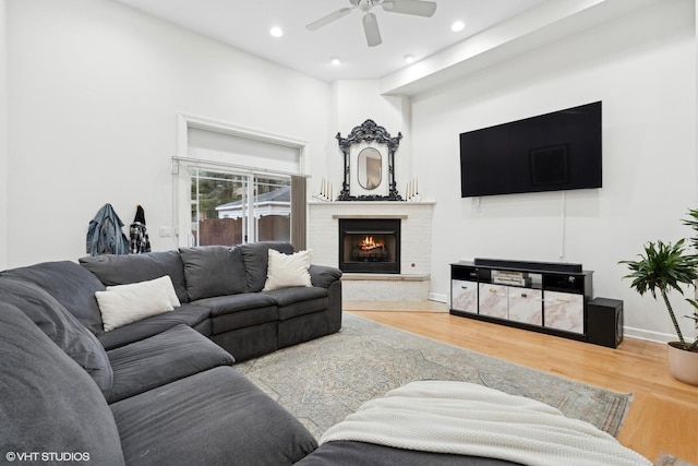 living area with a fireplace, recessed lighting, a ceiling fan, wood finished floors, and baseboards