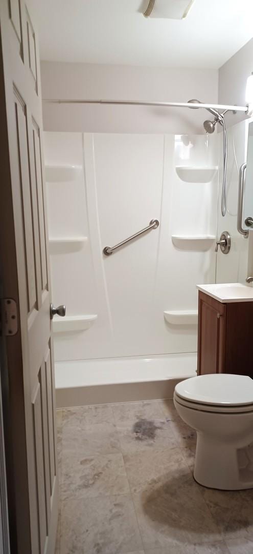 bathroom featuring vanity, toilet, and walk in shower