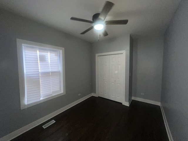 unfurnished bedroom featuring dark wood-type flooring, a closet, and ceiling fan