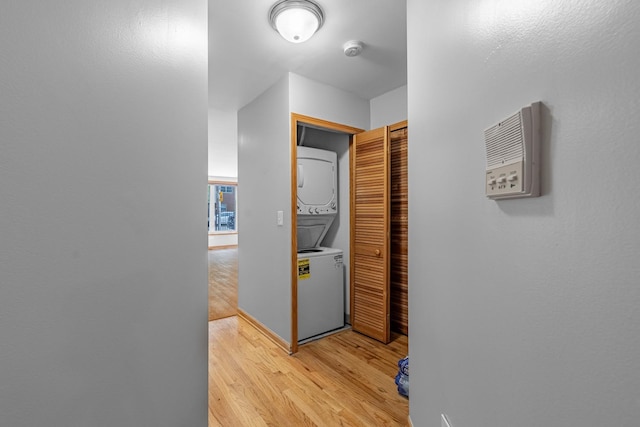 hallway with light hardwood / wood-style floors and stacked washer / dryer