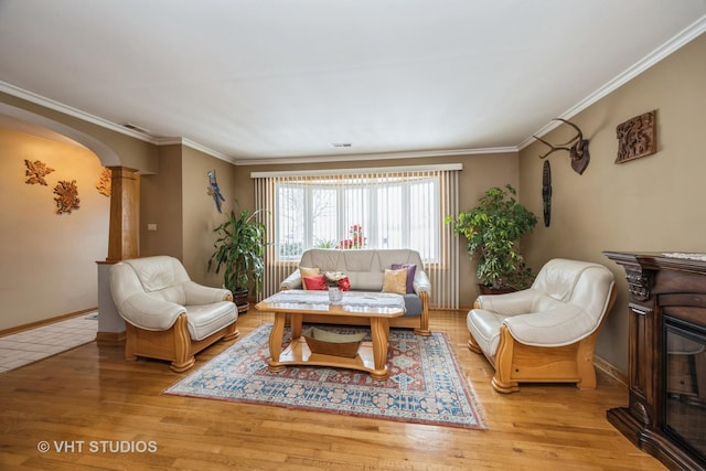 living room with crown molding, arched walkways, decorative columns, and wood finished floors