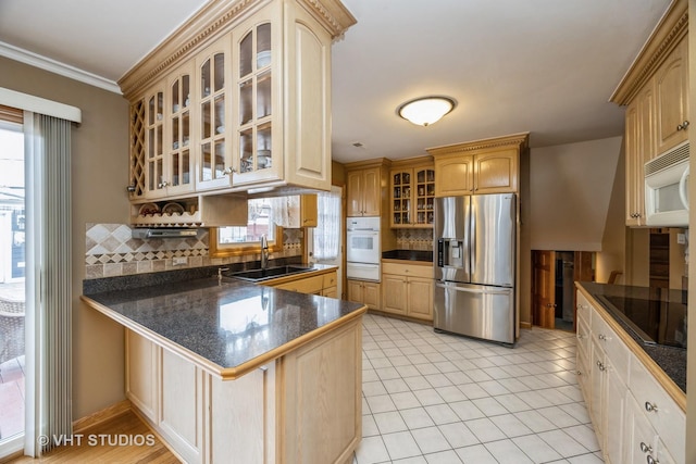 kitchen with dark countertops, white appliances, a sink, and a peninsula