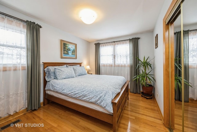 bedroom with light wood finished floors, a closet, visible vents, and baseboards