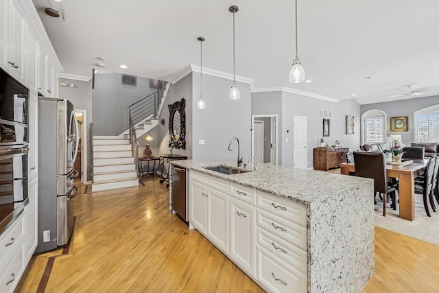 kitchen with pendant lighting, white cabinetry, a center island with sink, and a sink