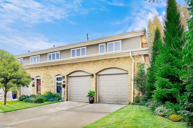 multi unit property with a garage, a front yard, concrete driveway, and brick siding